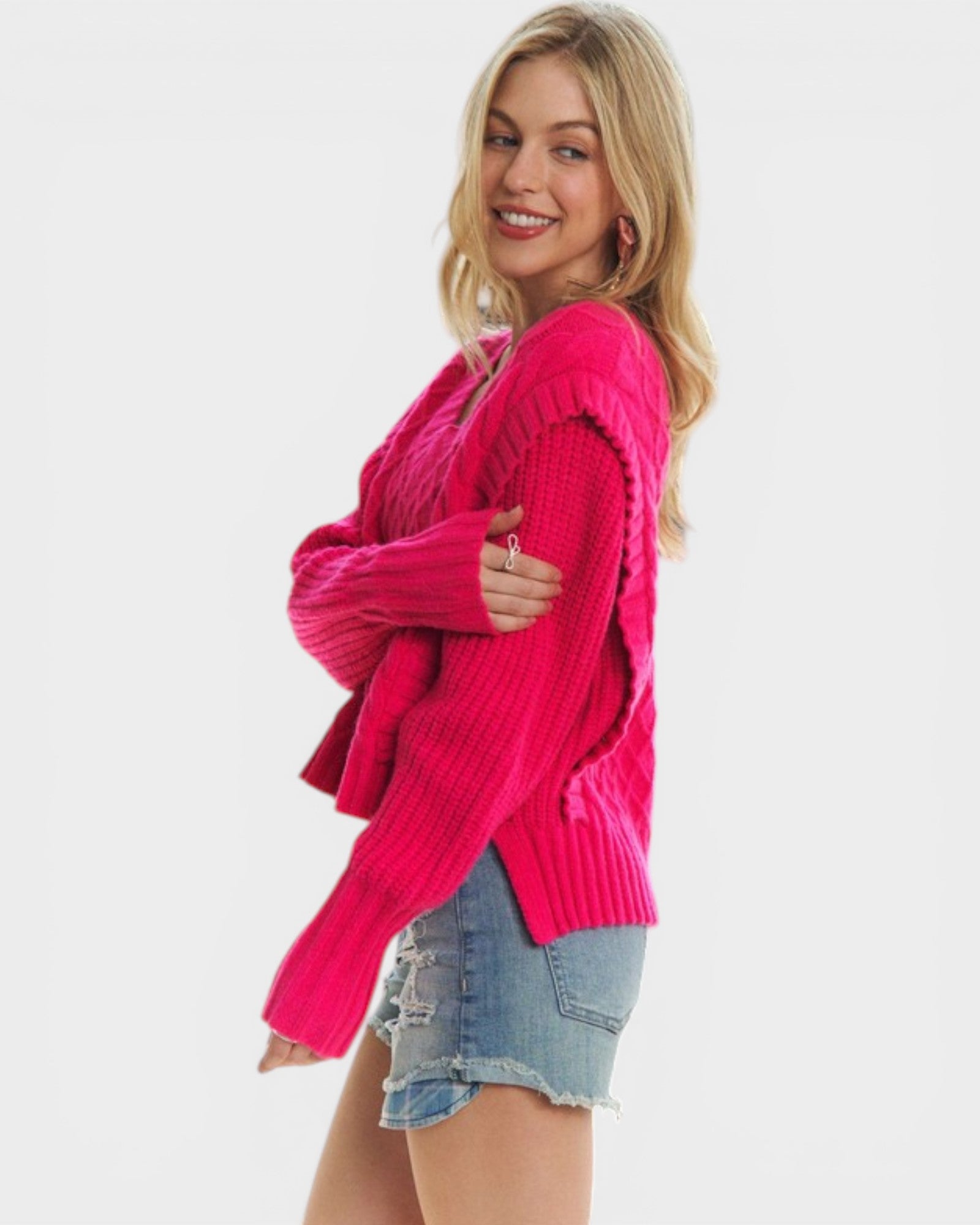 Woman wearing a bright pink cardigan over a denim shirt on a white background