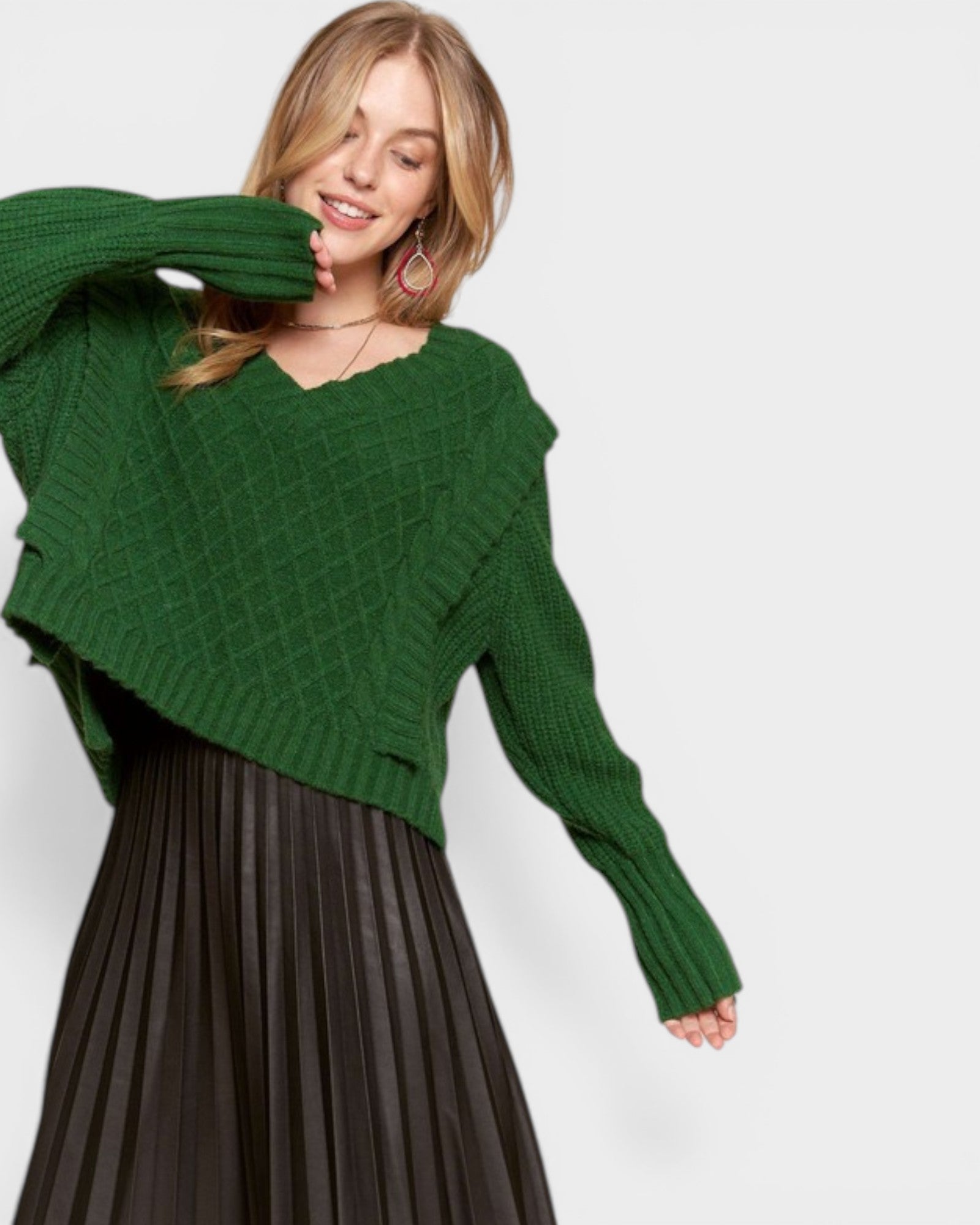 Woman wearing a green sweater and black pleated skirt on a white background