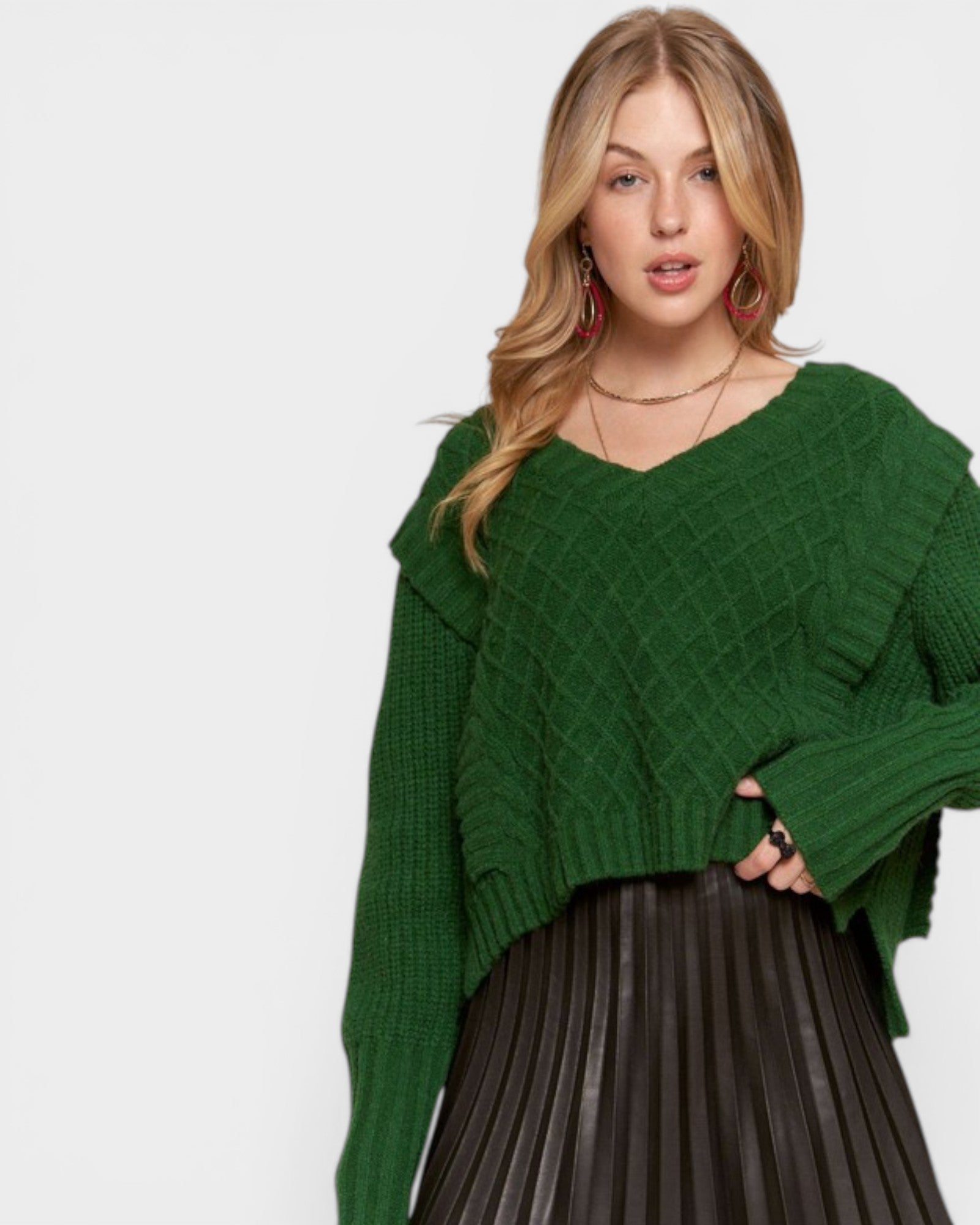 Woman wearing a green sweater and black pleated skirt on a white background