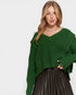 Woman wearing a green sweater and black pleated skirt on a white background