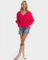 Woman wearing a bright pink sweater, denim shorts, and pink knee-high boots on a white background