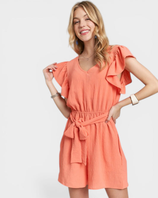 Woman wearing a coral romper on a white background