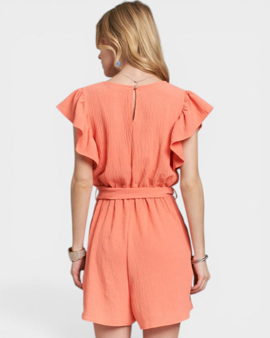 Woman wearing a coral dress with ruffled sleeves on a white background