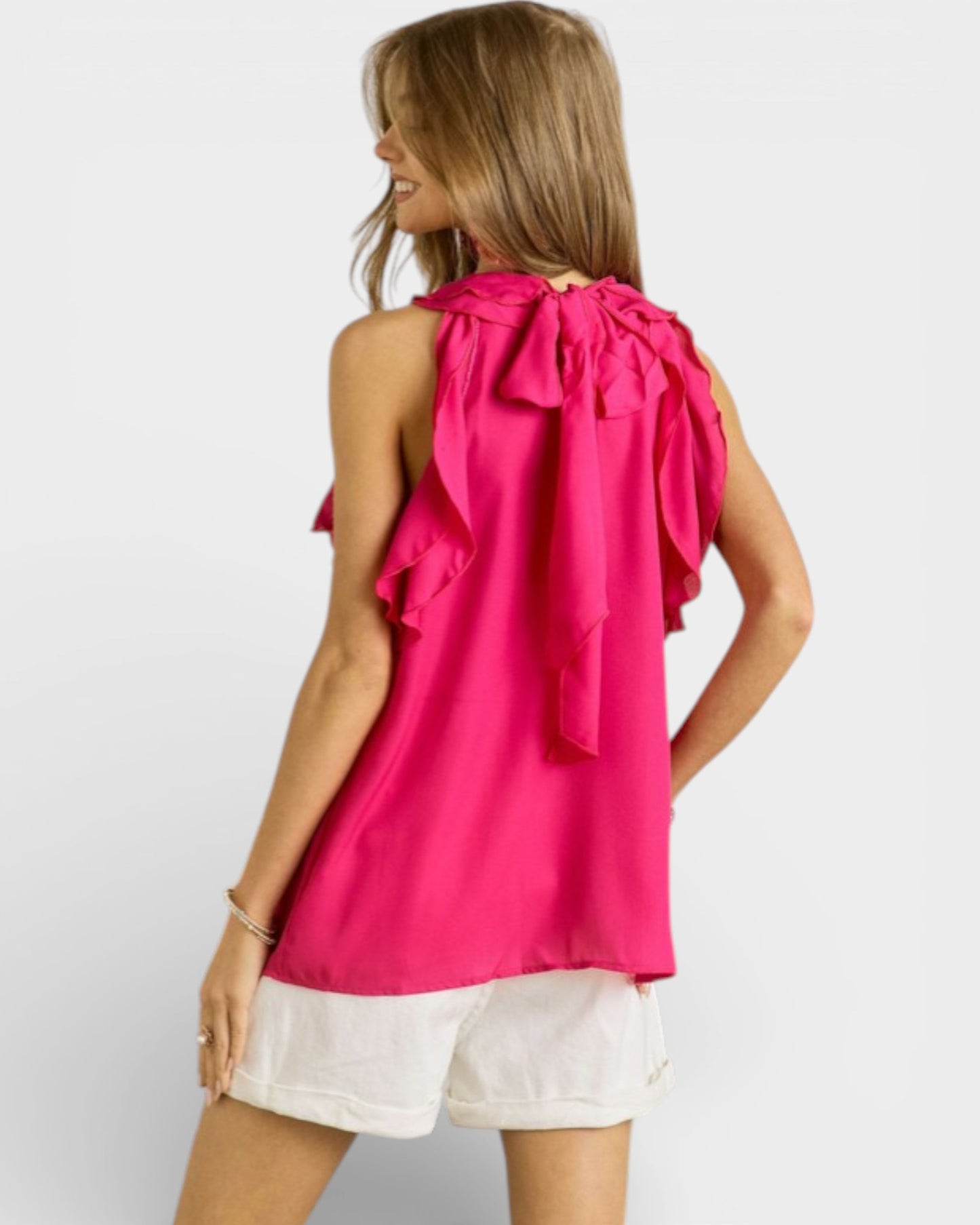 Woman wearing a bright pink halter top with ruffles on a white background