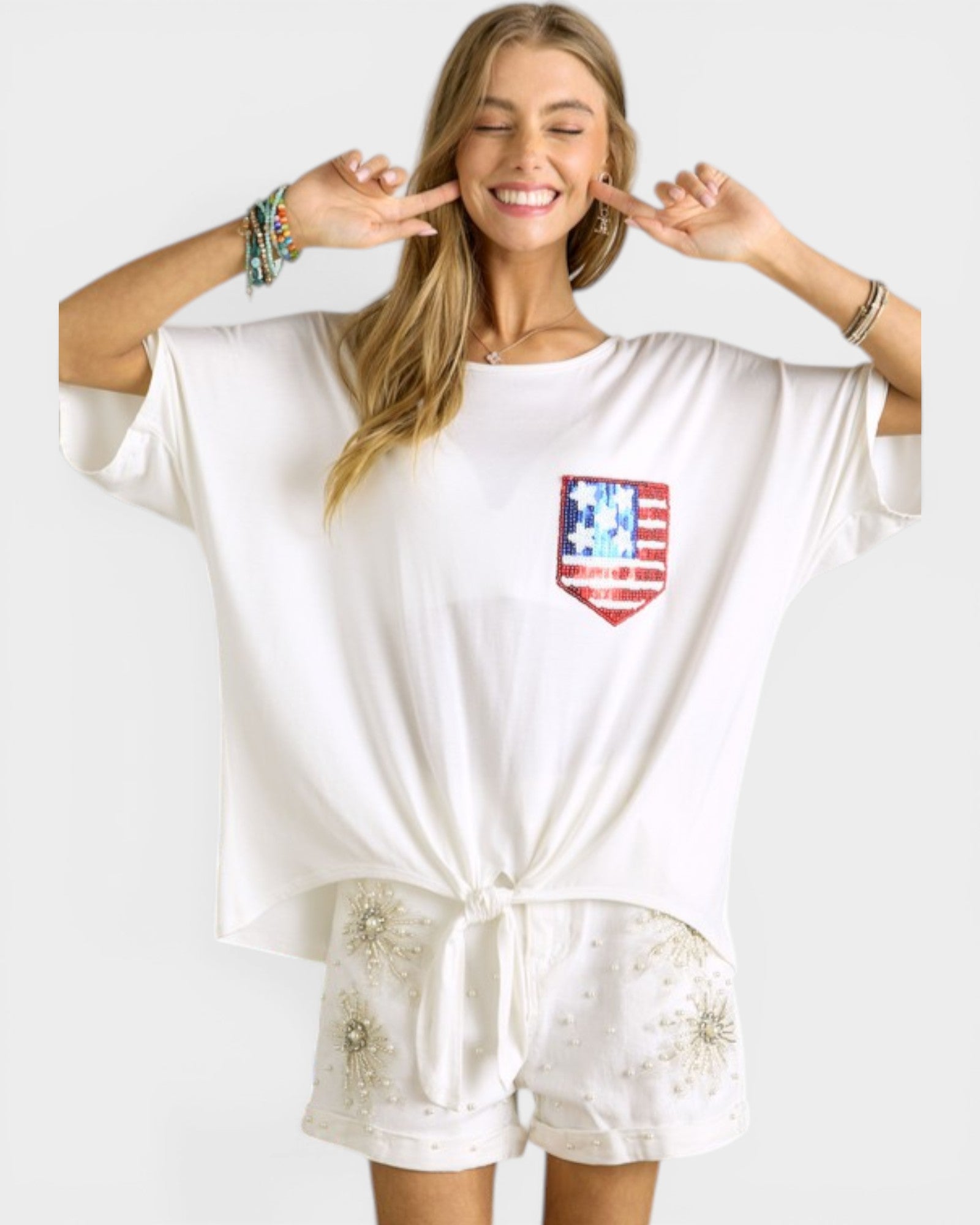 Woman wearing a white outfit with a red, white, and blue flag design on a plain background