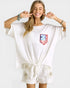 Woman wearing a white outfit with a red, white, and blue flag design on a plain background