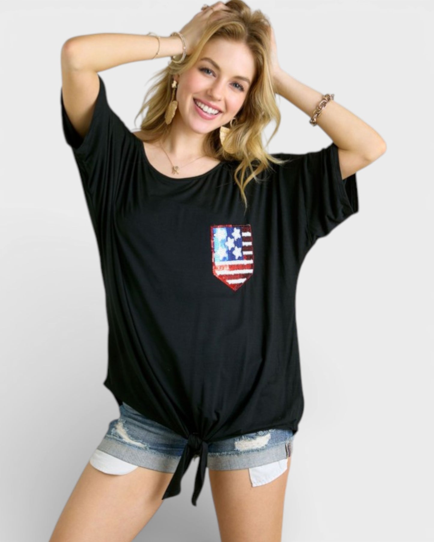 Woman wearing a black t-shirt with a red, white, and blue graphic on a plain background