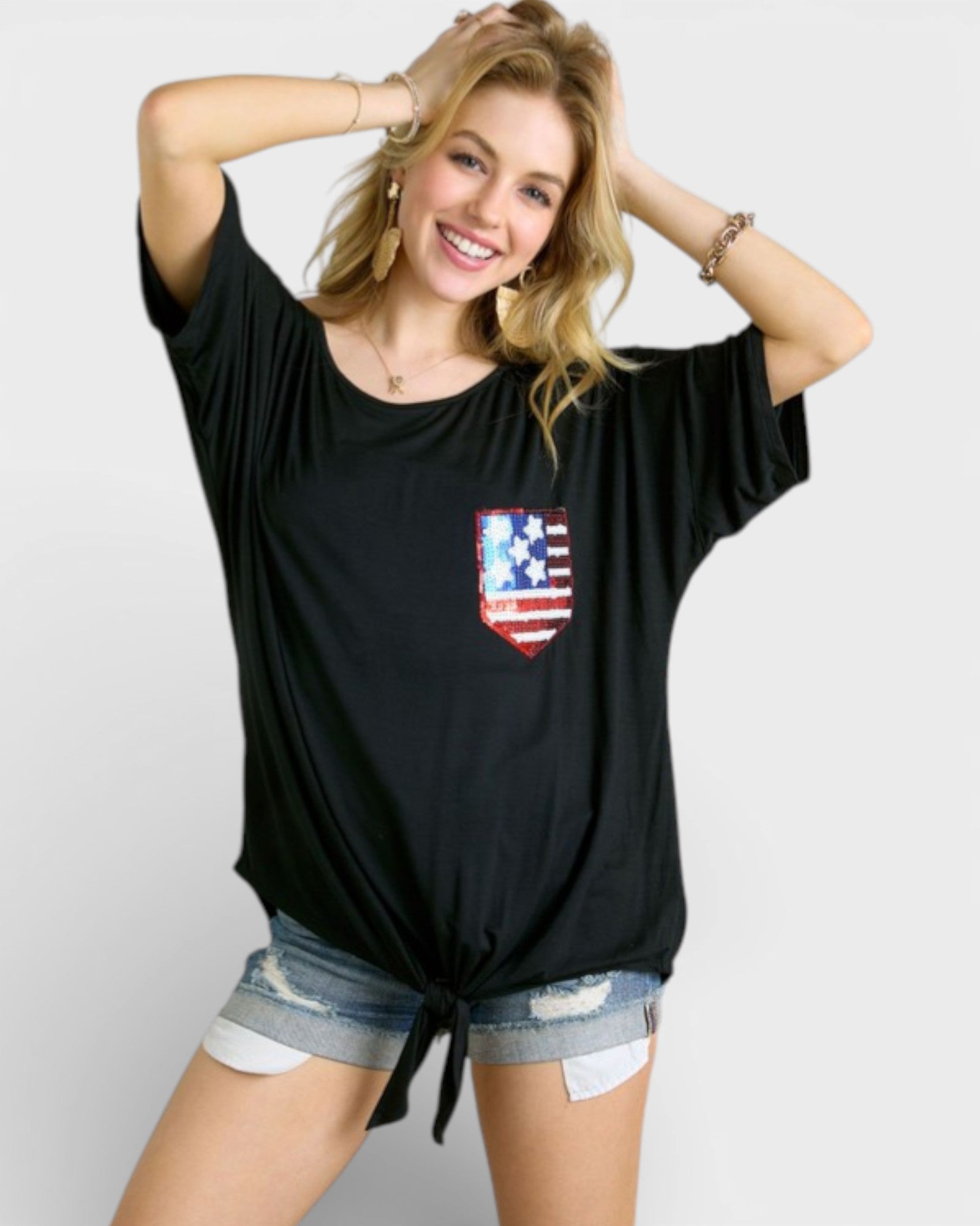 Woman wearing a black t-shirt with a red, white, and blue graphic on a plain background