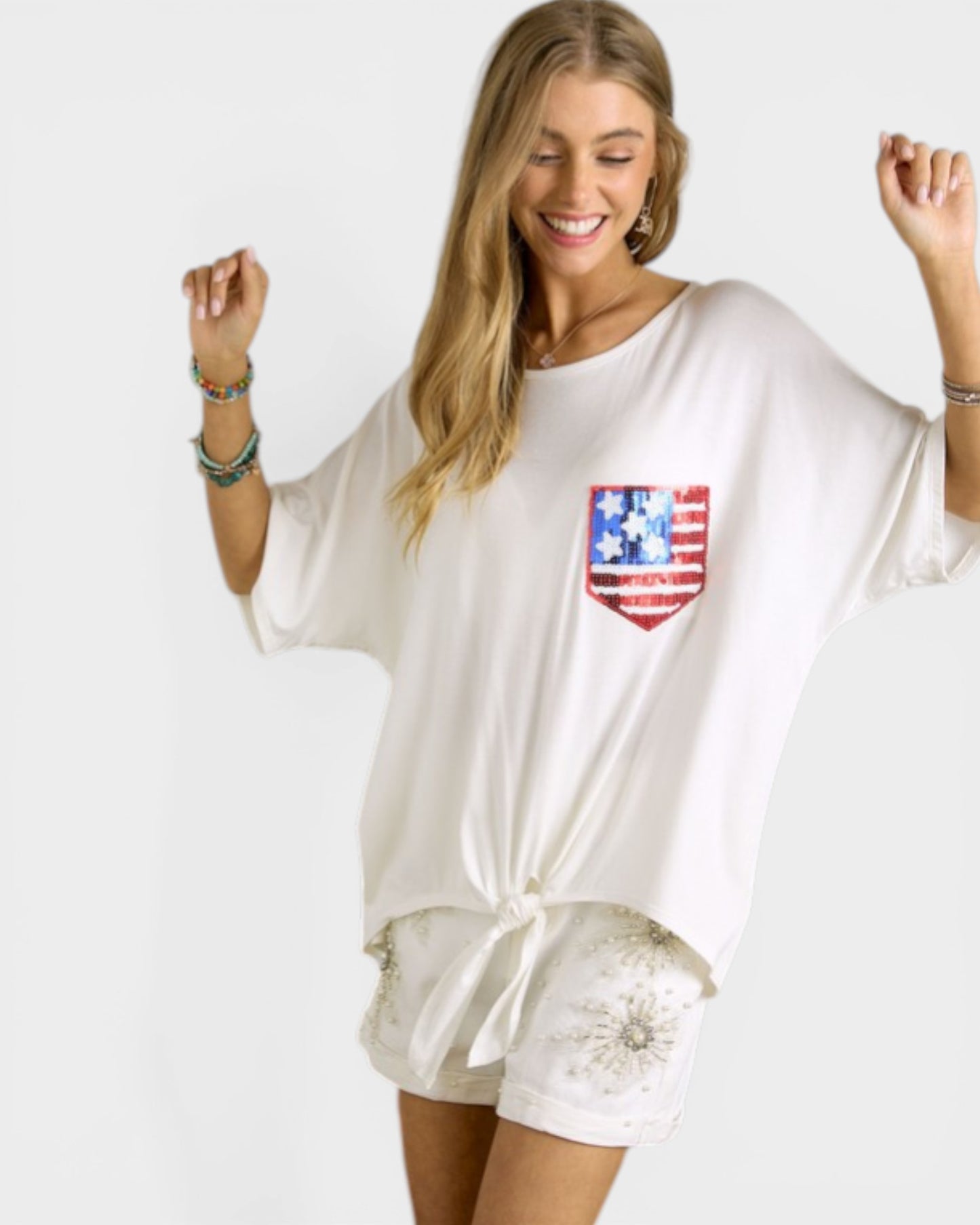 Woman wearing a white oversized shirt with a red, white, and blue flag design on a plain background