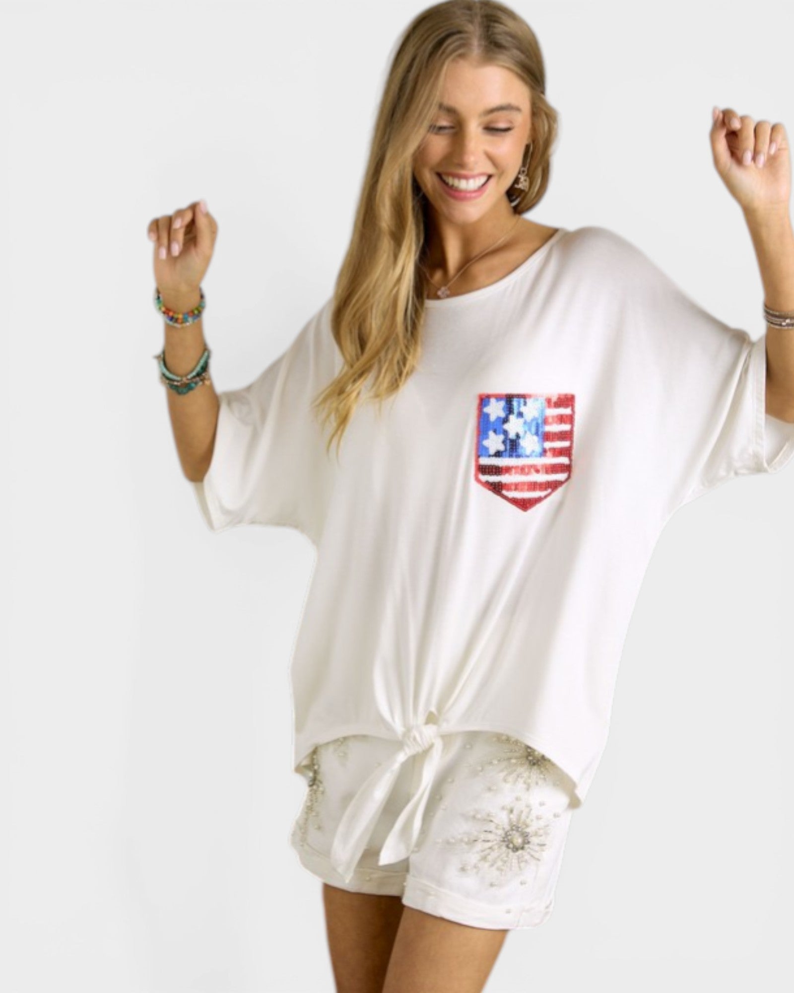 Woman wearing a white oversized shirt with a red, white, and blue flag design on a plain background