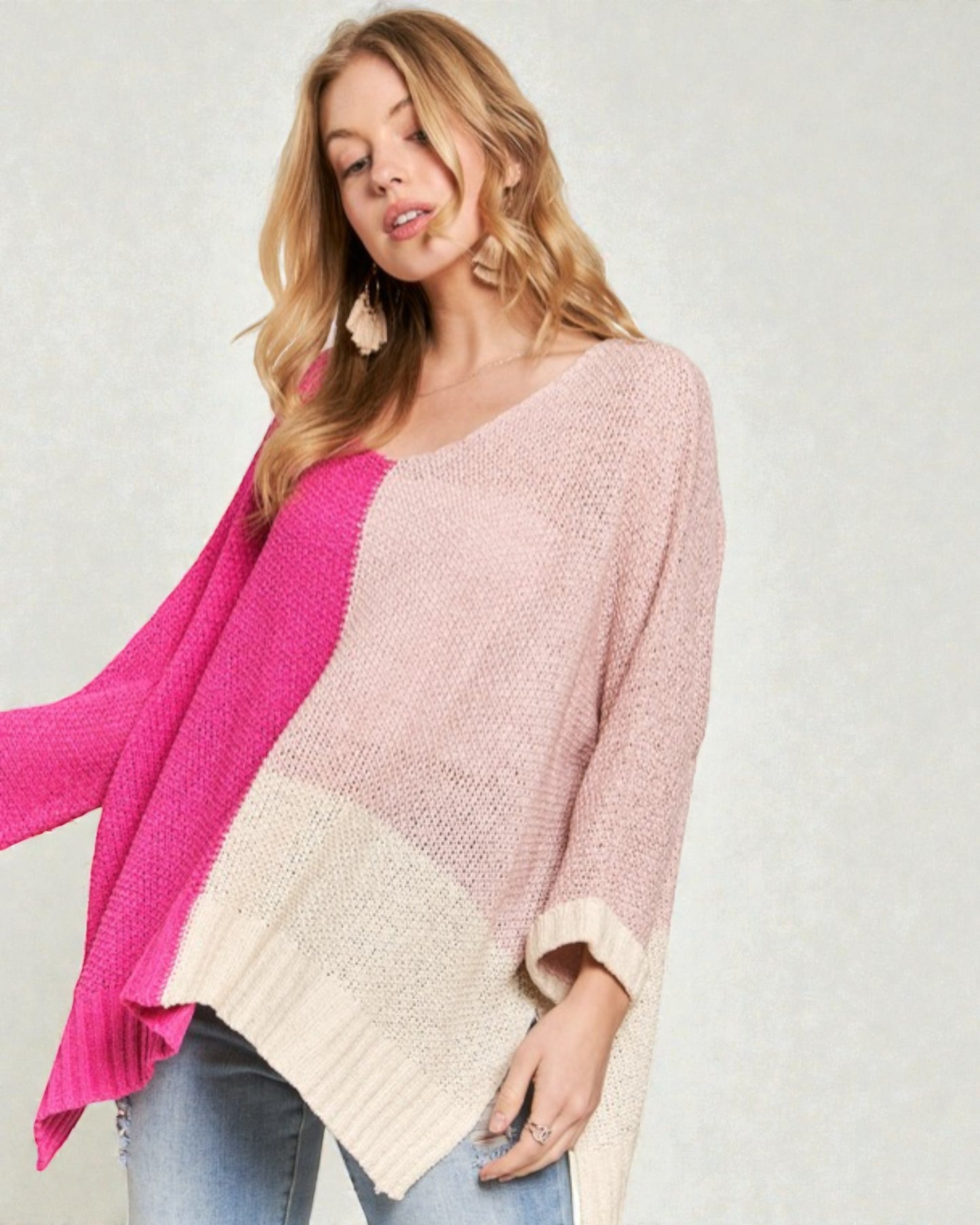 Woman wearing a pink and beige color-blocked sweater on a plain background