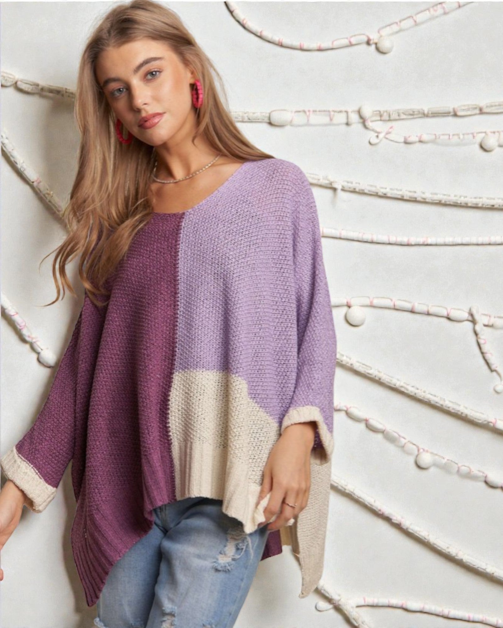 Woman wearing a colorful sweater against a decorative wall.