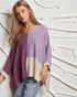 Woman wearing a colorful sweater against a decorative wall.