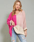 Woman wearing a pink and white sweater with a beige clutch against a gray background