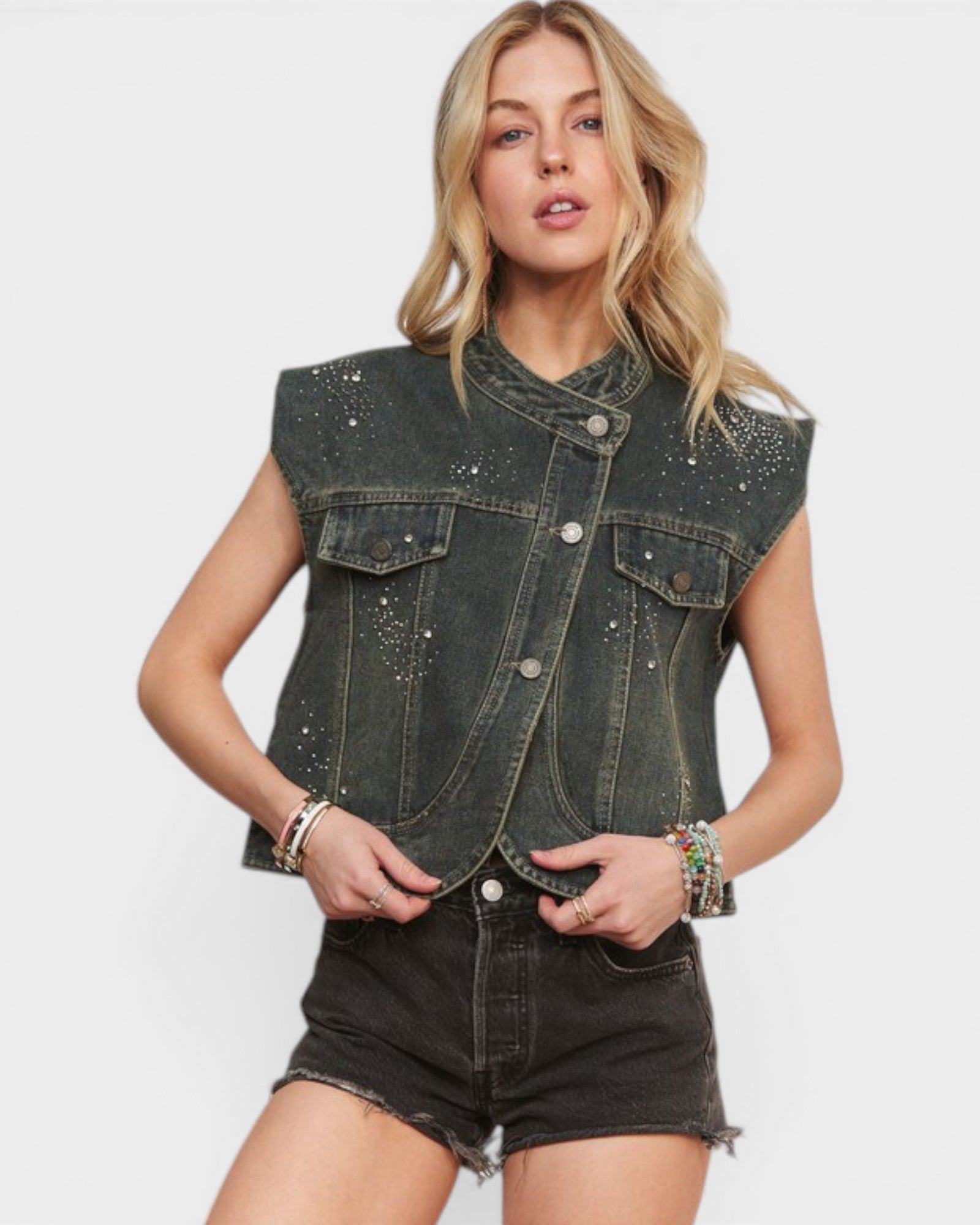 Woman wearing a black denim vest with embellishments on a white background