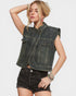 Woman wearing a denim vest with embellishments on a plain background