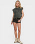 Woman wearing a denim vest, shorts, and boots on a white background