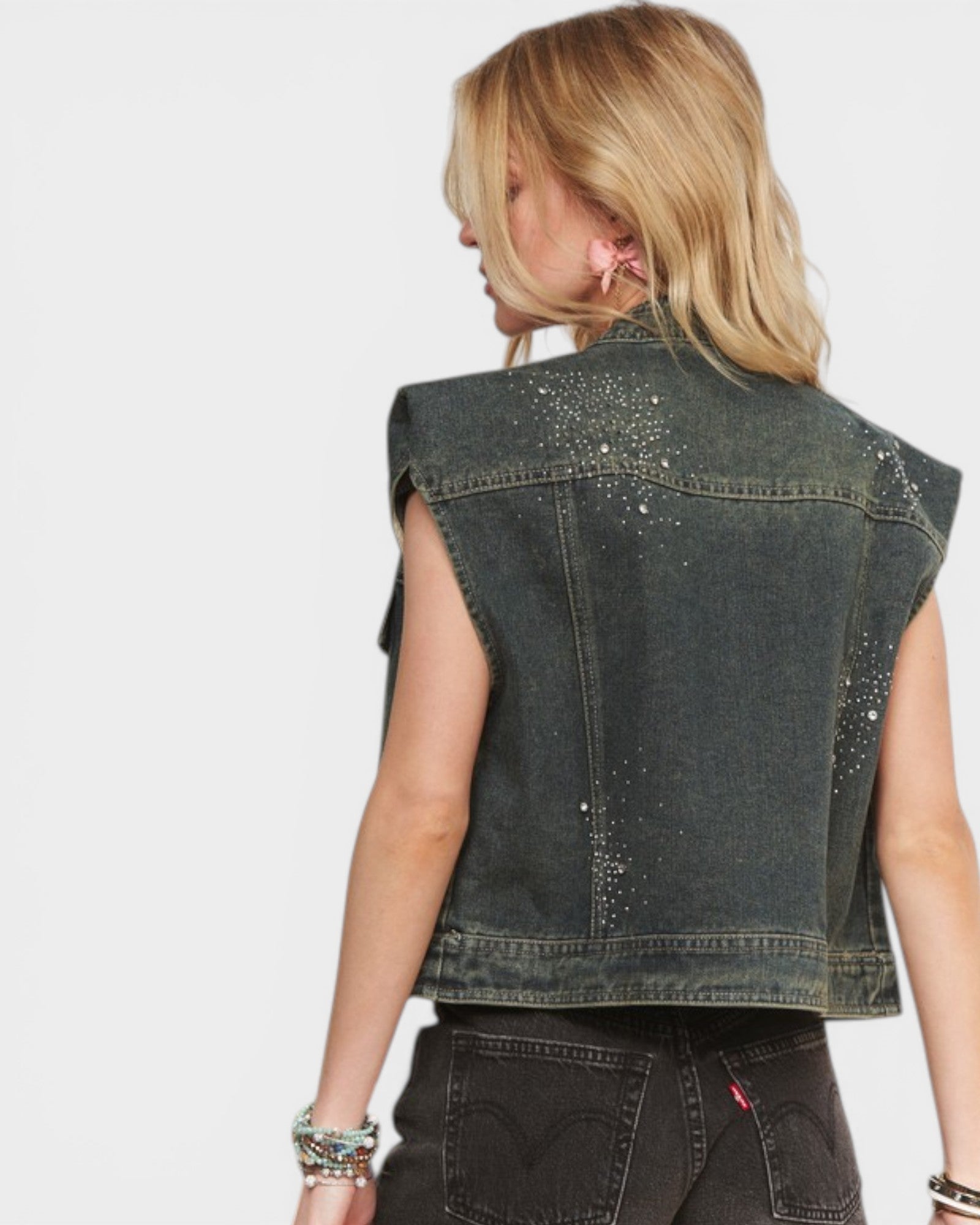 Denim vest with embellishments on a plain background