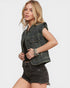 Woman wearing a black denim vest over a black top with a white background