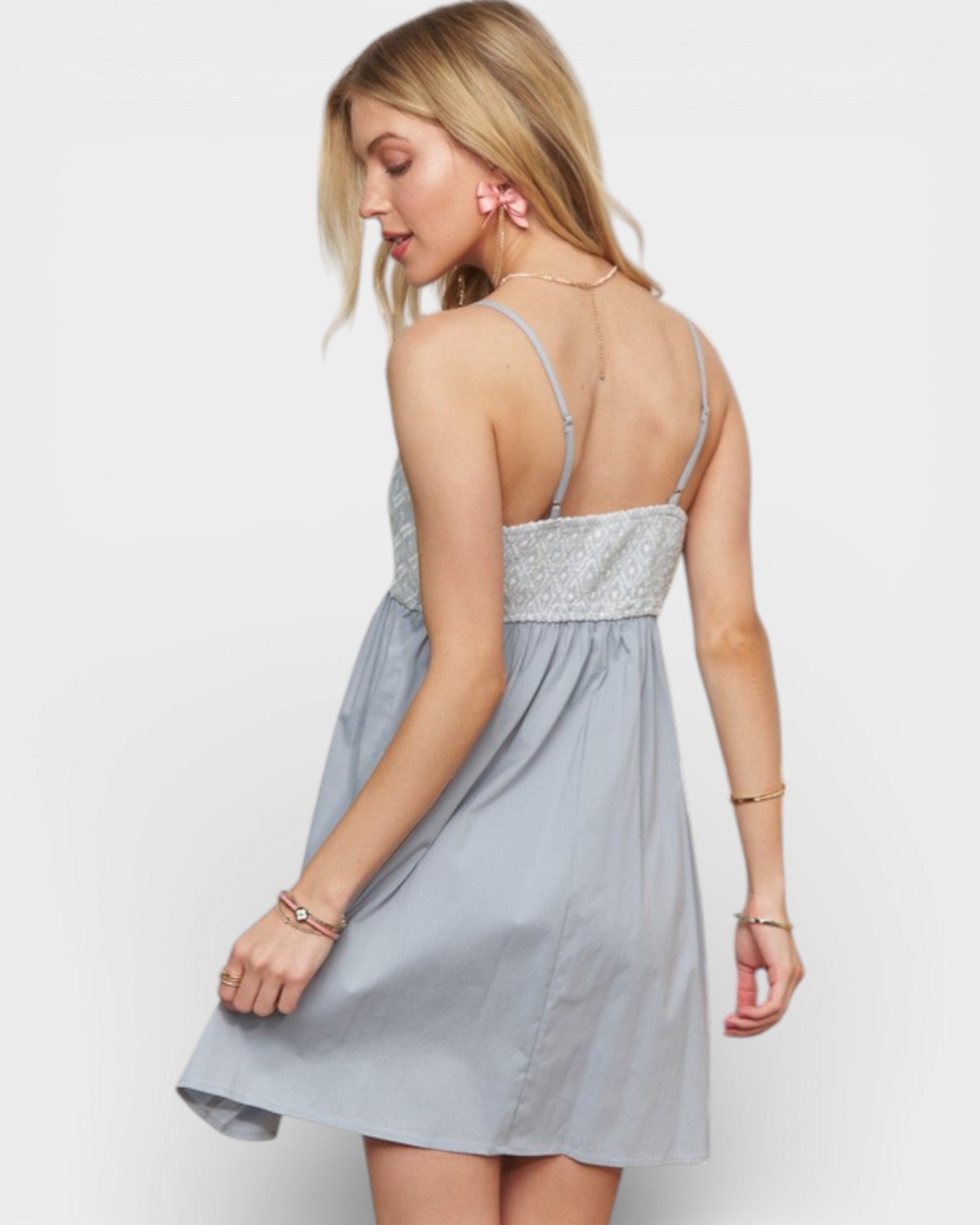 Woman wearing a light blue dress with a silver embellished top on a white background