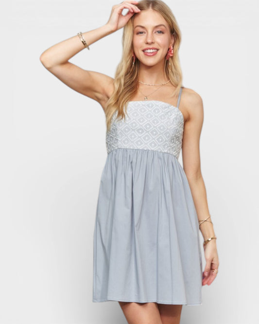 Woman wearing a light blue dress with lace details on a white background