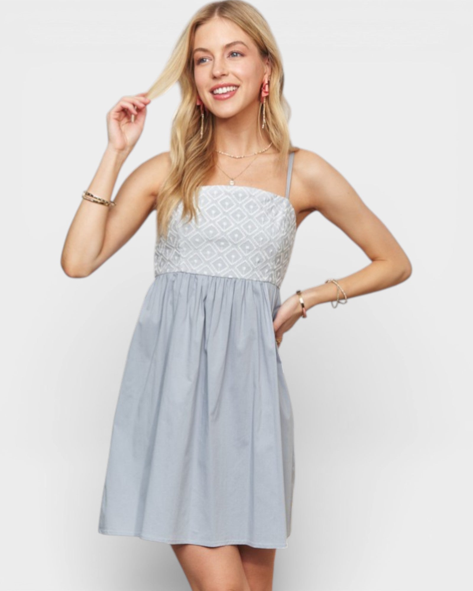 Woman wearing a light blue dress with a white lace top on a plain background