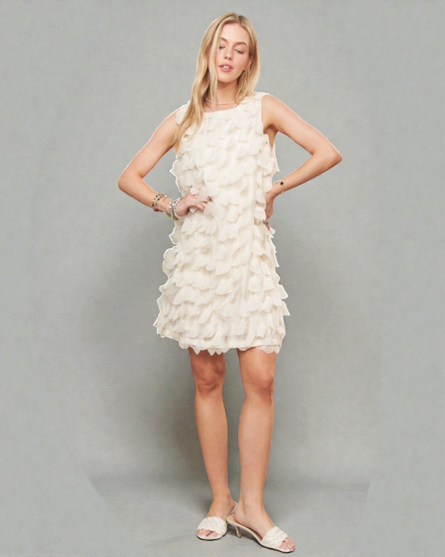 Woman wearing a white ruffled dress against a gray background