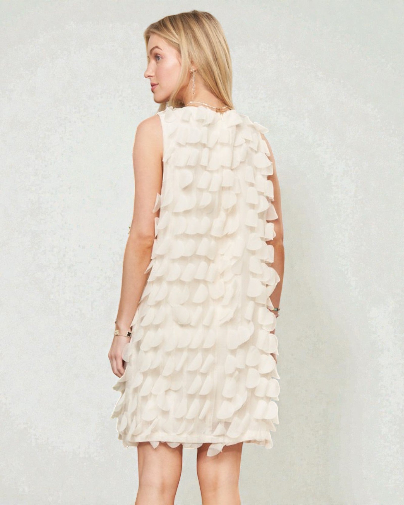 Woman wearing a white ruffled dress against a plain background