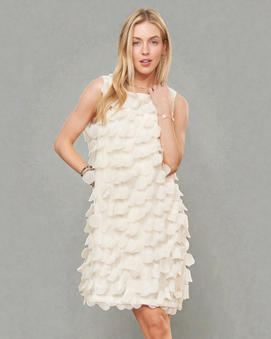 Woman wearing a white dress with floral details against a gray background