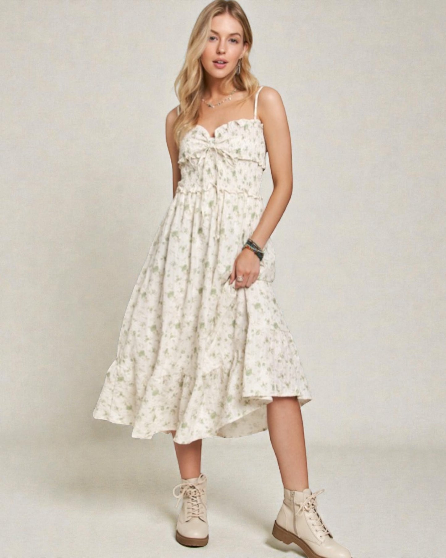 Woman wearing a white floral dress with beige boots on a plain background