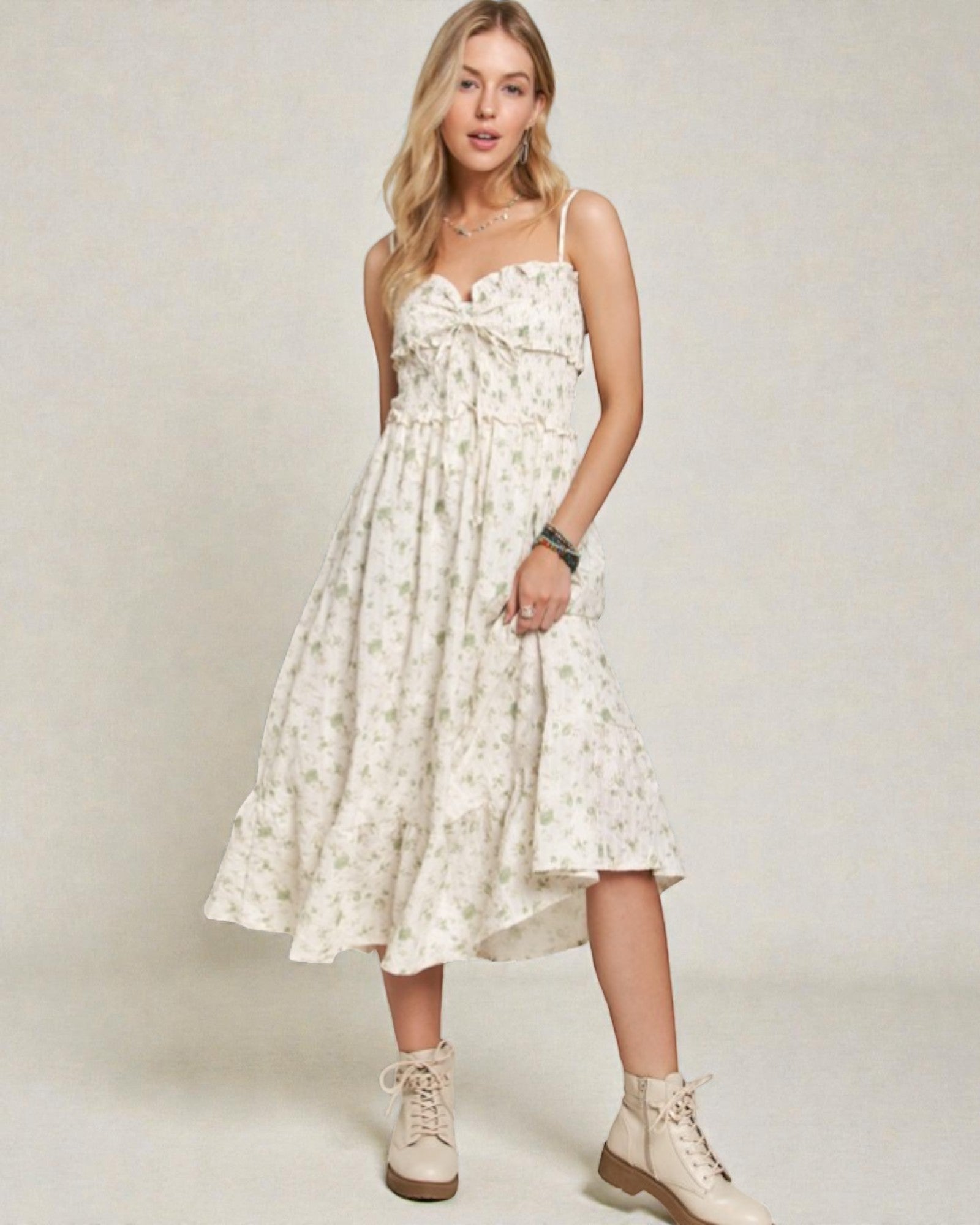 Woman wearing a white floral dress with beige boots on a plain background