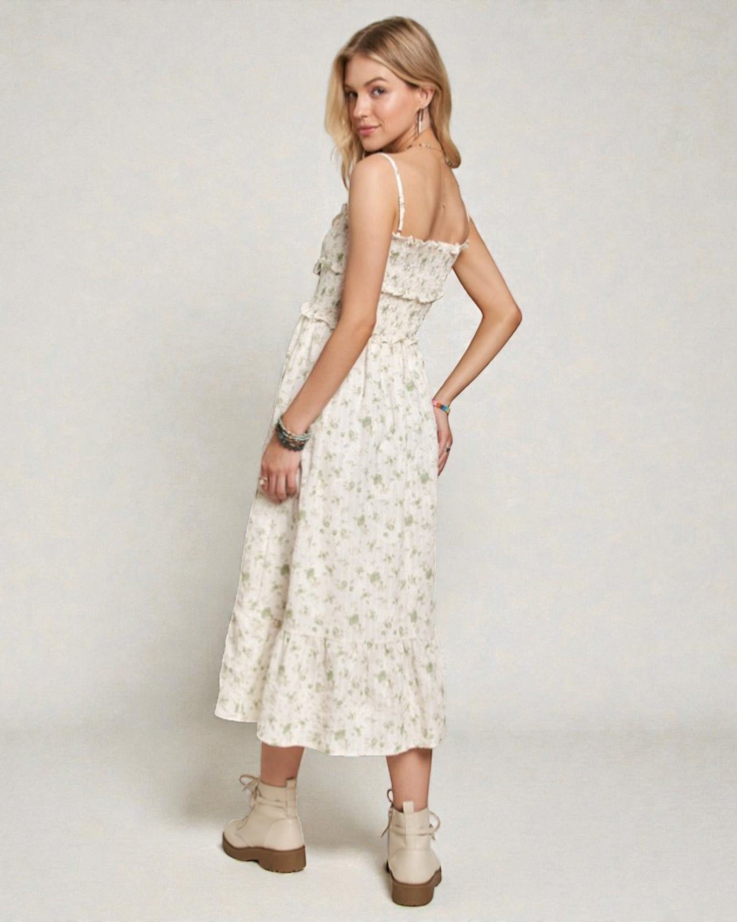 Woman wearing a floral dress with beige boots on a plain background