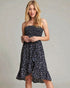 Woman wearing a strapless navy dress with white floral pattern on a gray background