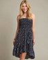 Woman wearing a strapless floral dress against a plain background