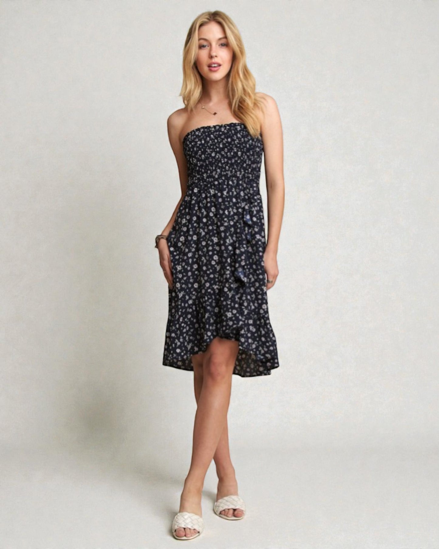 Woman wearing a black floral strapless dress on a plain background