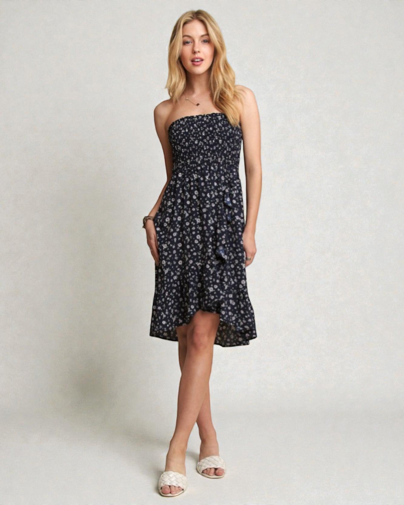 Woman wearing a black floral strapless dress on a plain background