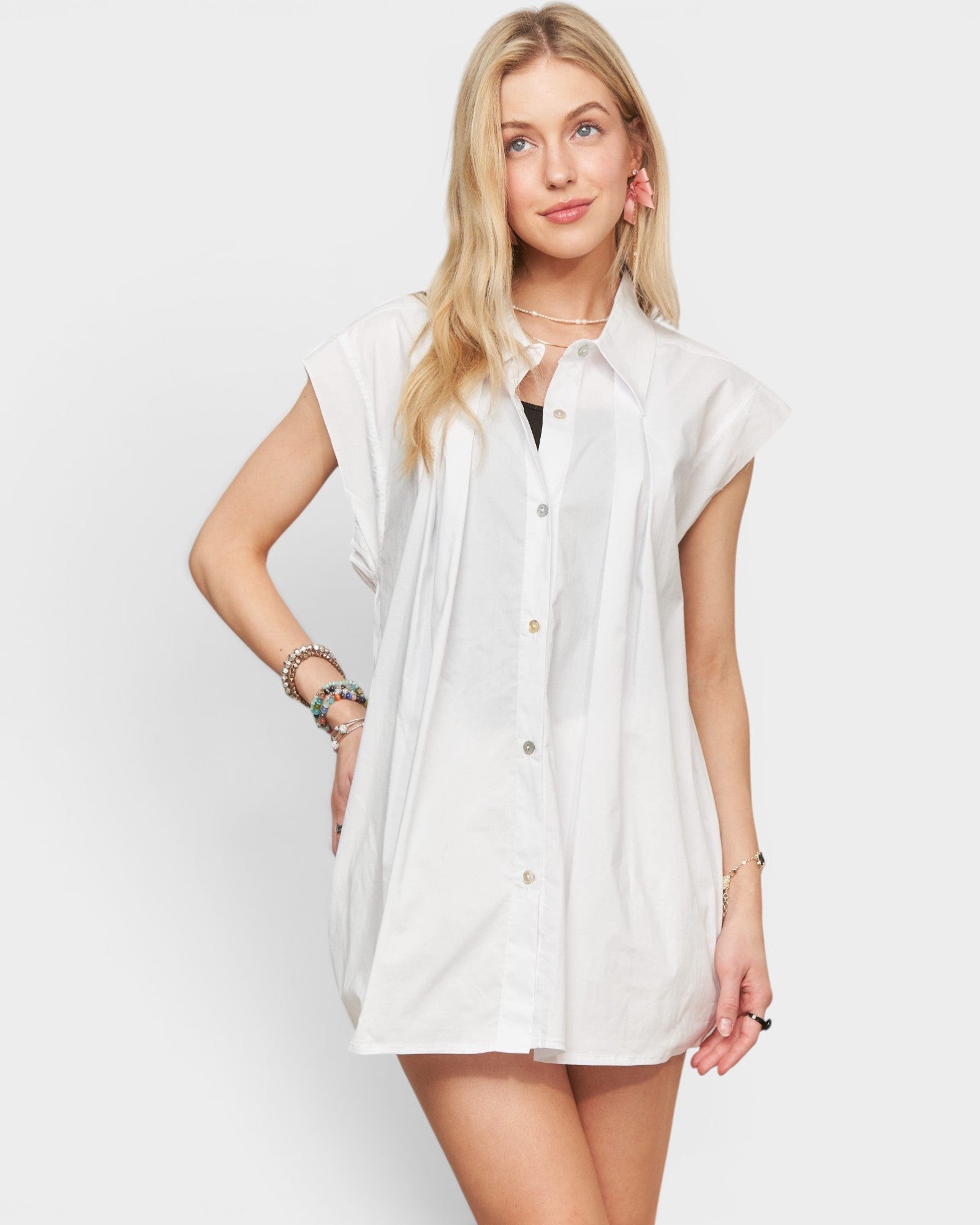 Woman wearing a white sleeveless shirt against a plain background