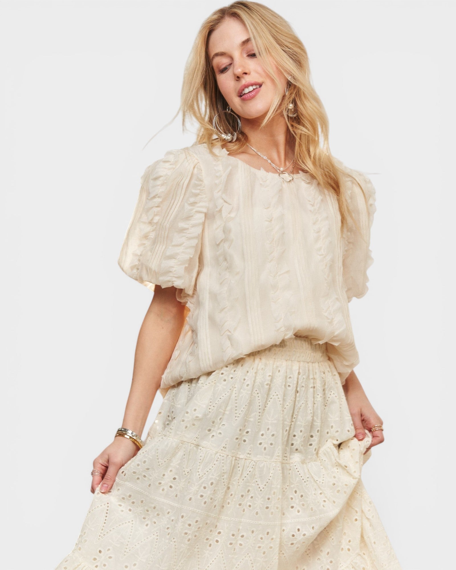 Woman wearing a cream-colored dress with puff sleeves on a white background