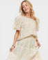 Woman wearing a cream-colored dress with puff sleeves on a white background