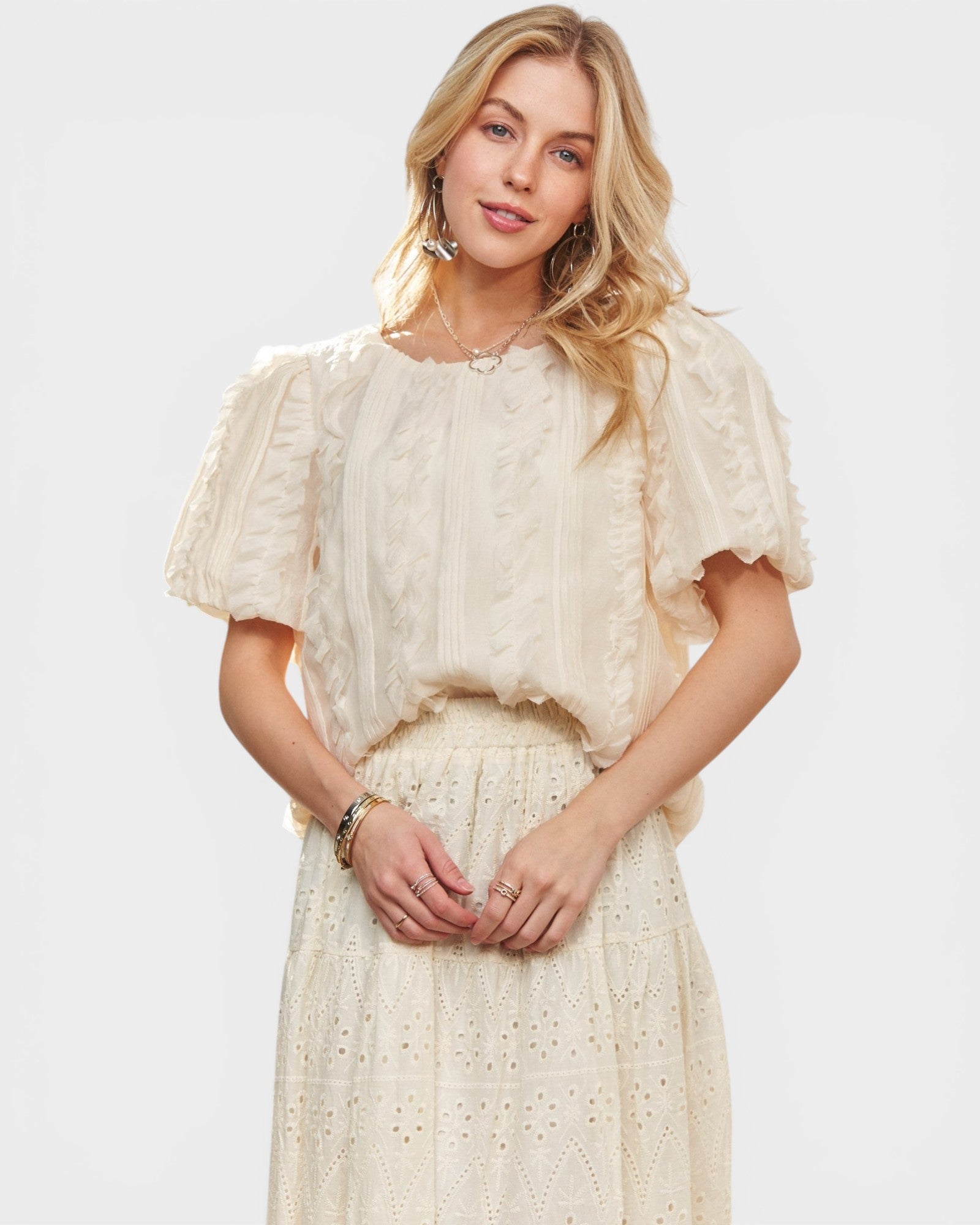 Woman wearing a beige dress with ruffled sleeves against a white background