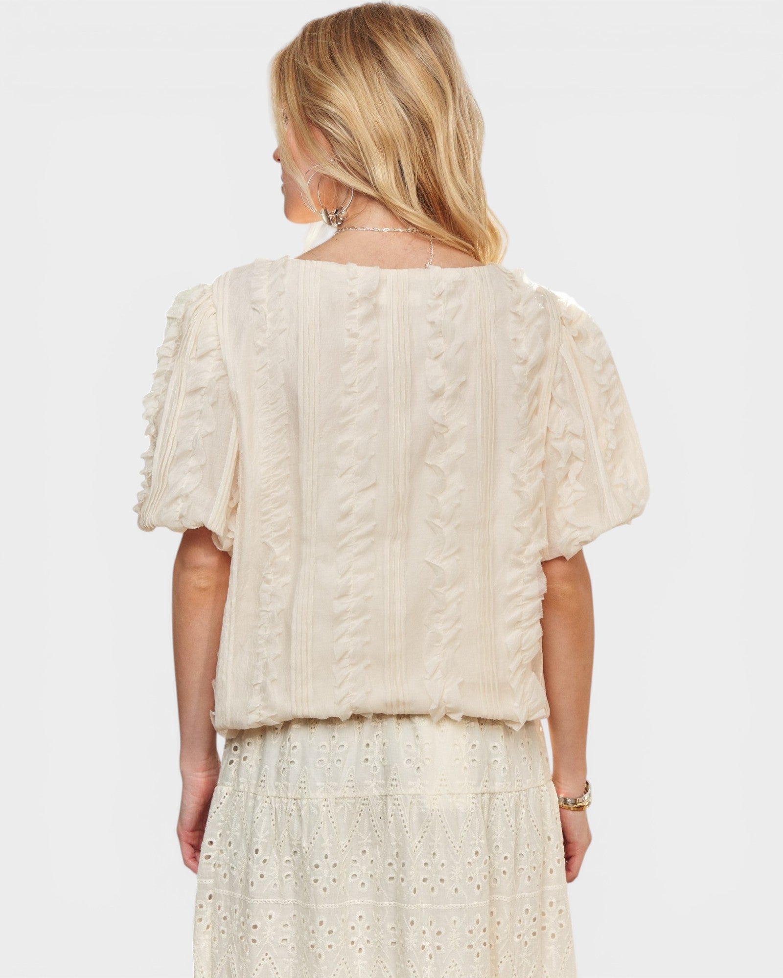 Woman wearing a cream-colored knit top and skirt set on a white background