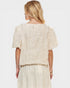 Woman wearing a cream-colored knit top and skirt set on a white background