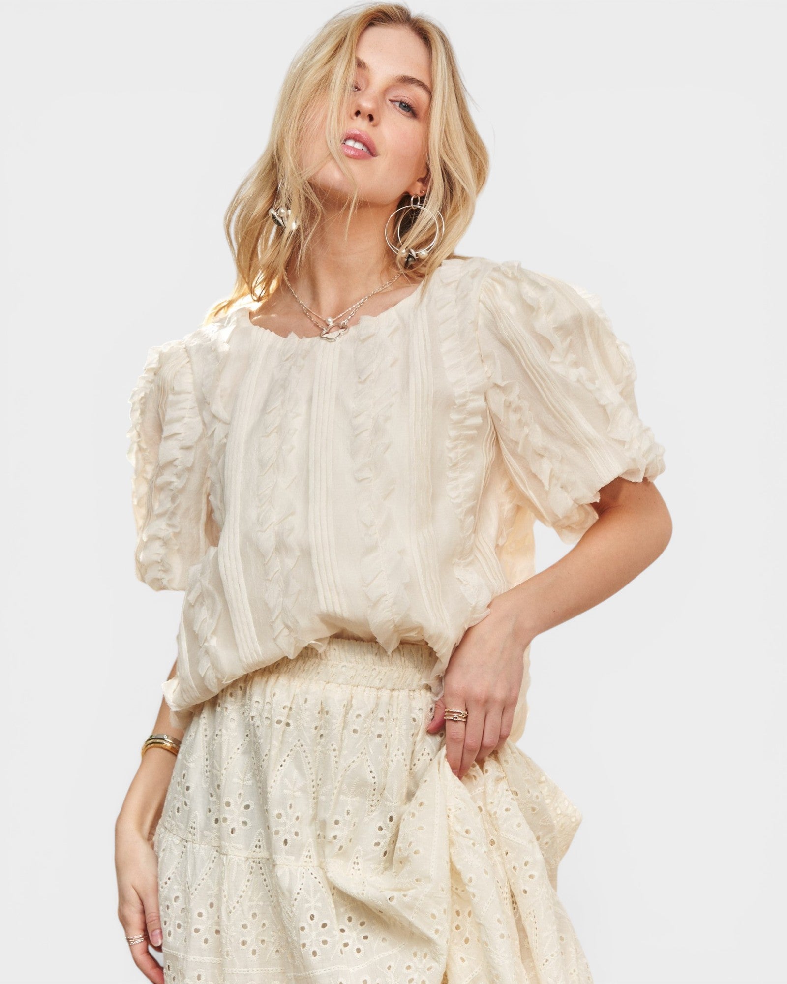 Woman wearing a cream-colored blouse and skirt set on a white background