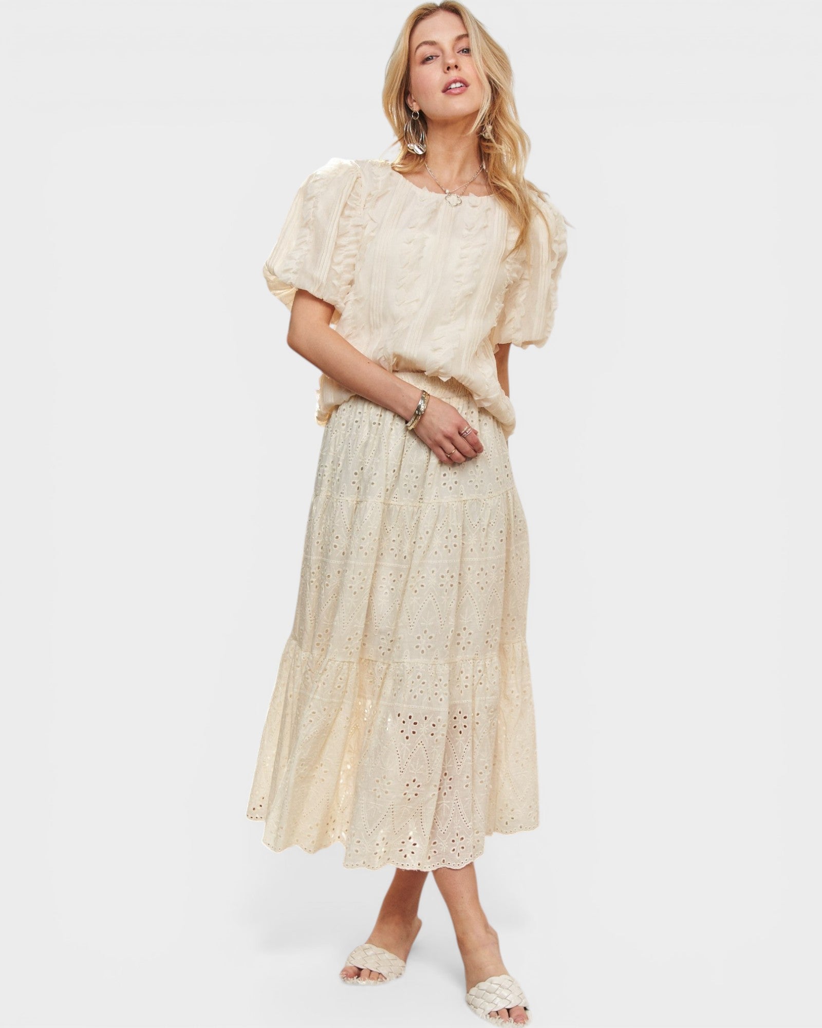 Woman wearing a cream lace outfit on a white background