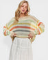 Woman wearing a colorful striped sweater with a plain background