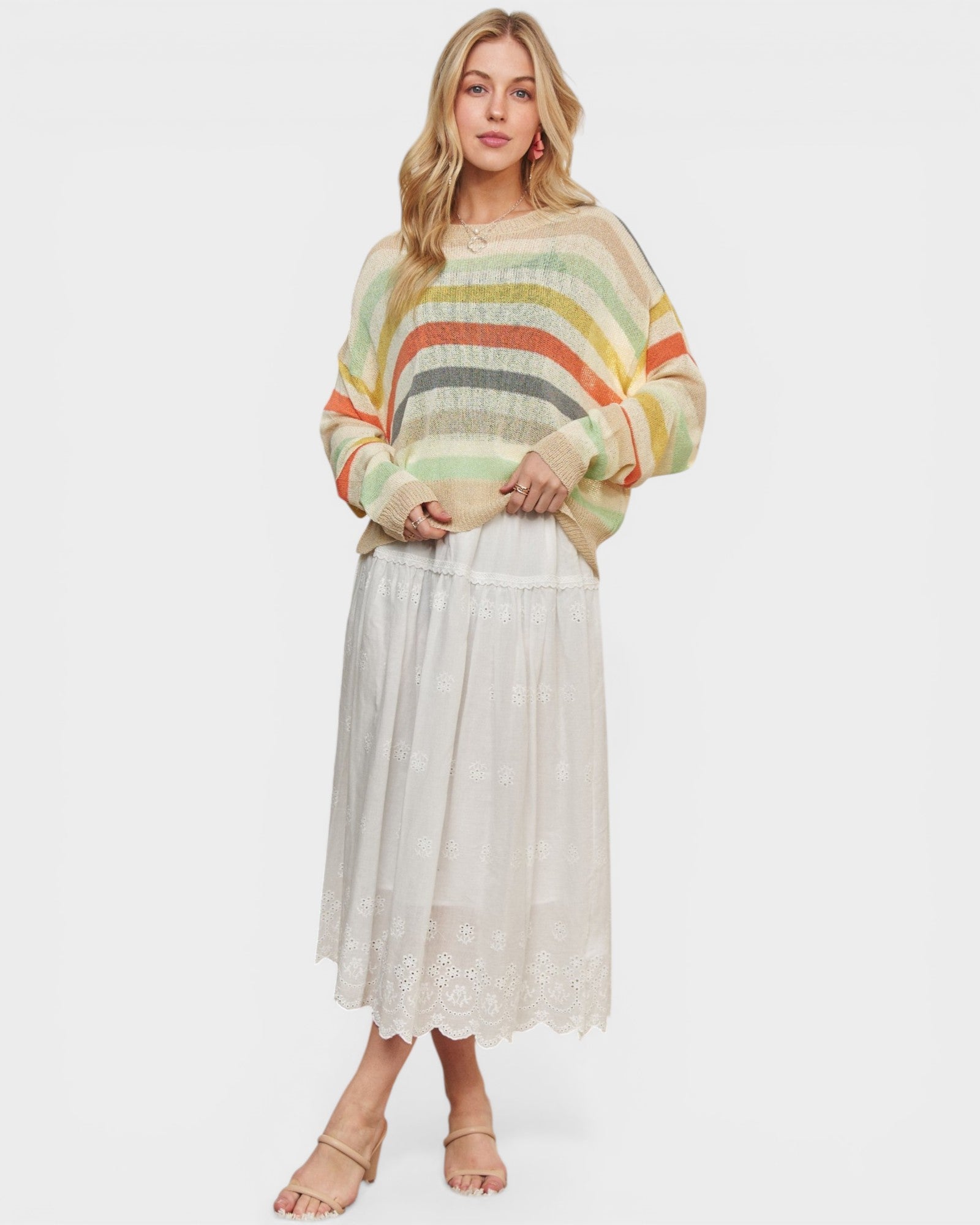 Woman wearing a colorful striped sweater and white skirt on a white background