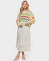 Woman wearing a colorful striped sweater and white skirt on a white background