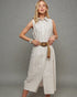 Woman wearing a white sleeveless dress with a belt against a gray background
