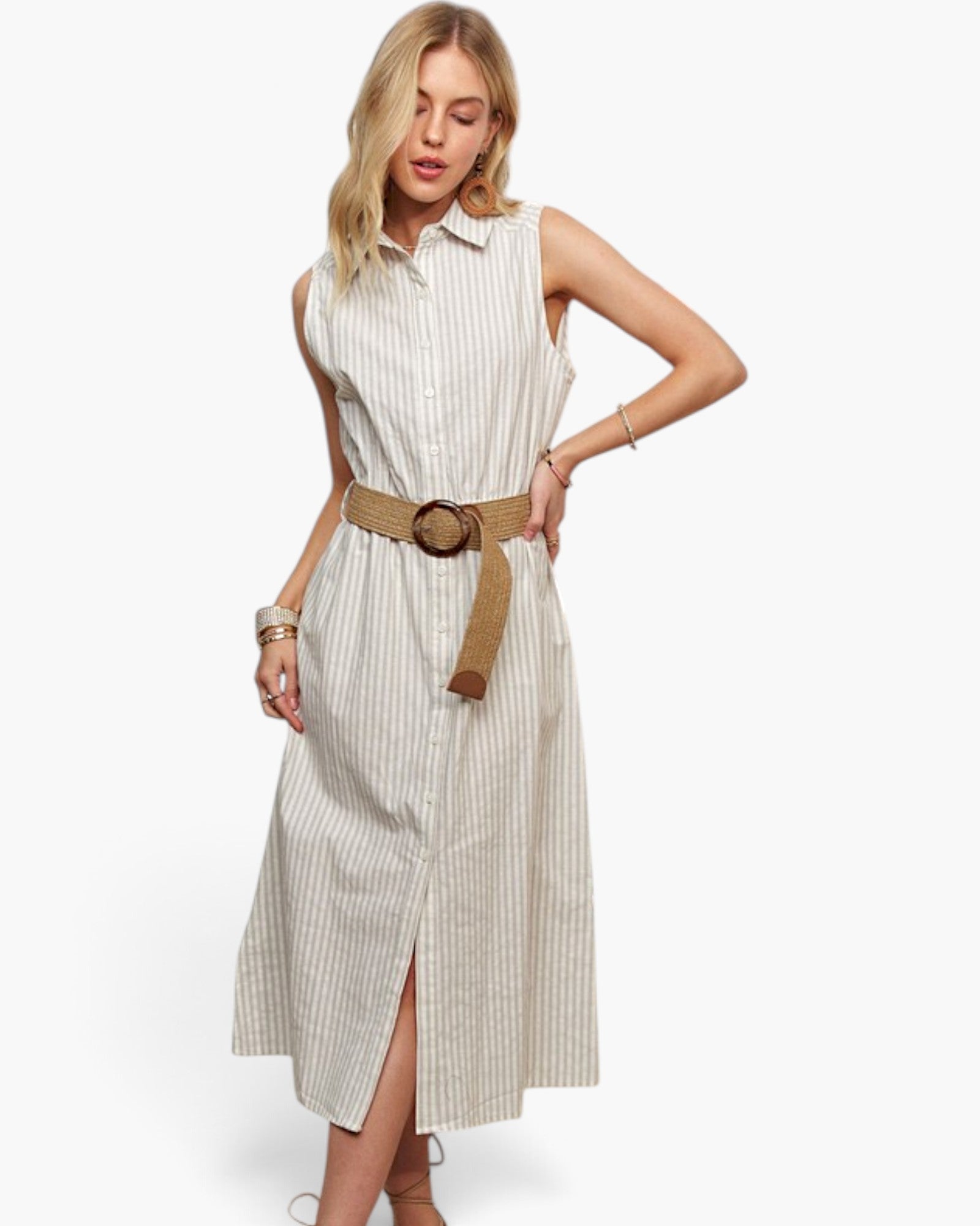 A woman models a sleeveless, button-front midi dress with vertical pinstripes in cream and beige, styled with a wide tan belt featuring a round wooden buckle, against a plain white studio background.