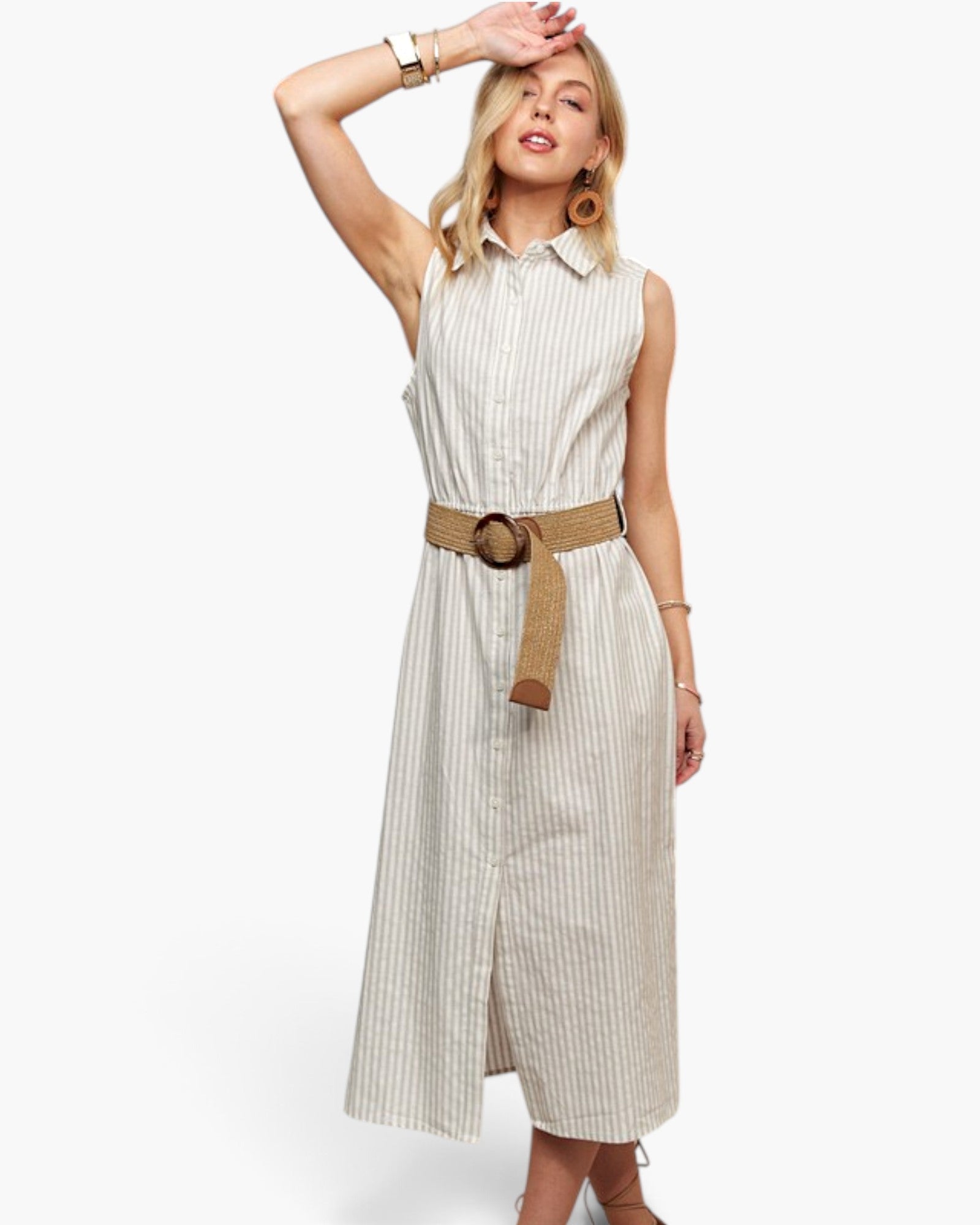 A woman modeling a sleeveless, button-front midi dress with thin vertical stripes in off-white and beige, featuring a tan woven belt with a round brown buckle.